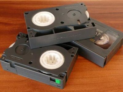 Stack of 3 VHS-C tapes on a wooden surface.