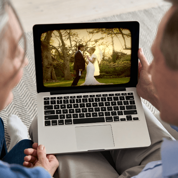 A couple enjoys a digitised slide of their wedding day on a laptop